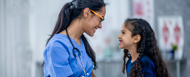A health professional (left) is talking to a child (right).