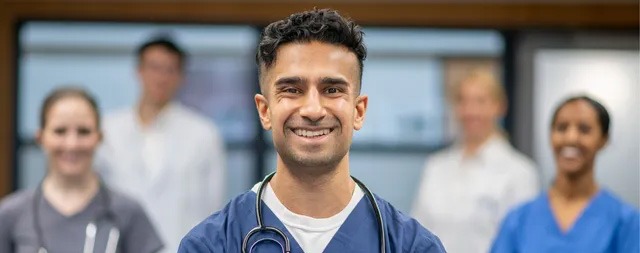 Five health professionals are standing together and smiling at the camera.